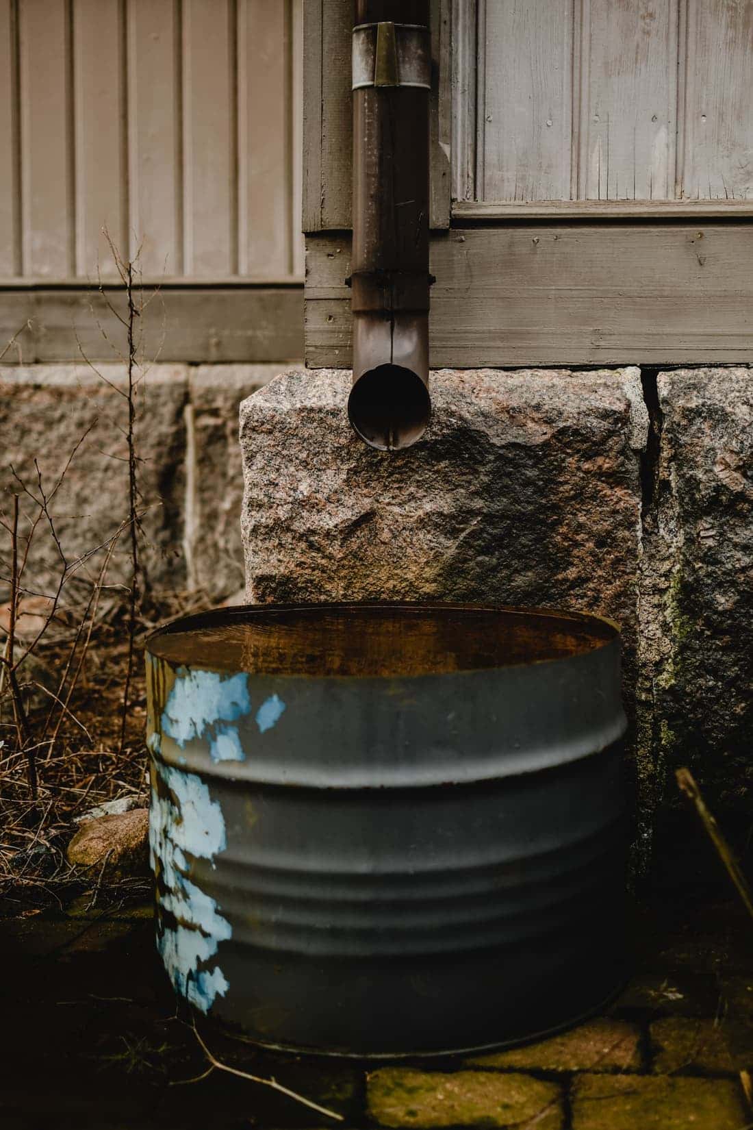 Downspout emptying beside a stone foundation